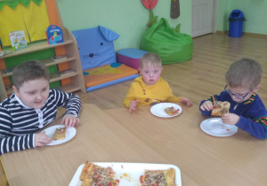 3 chłopców je pizzę.